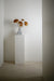 Concrete vase in hallway on white pedestal with bouquet of dried hydrangea